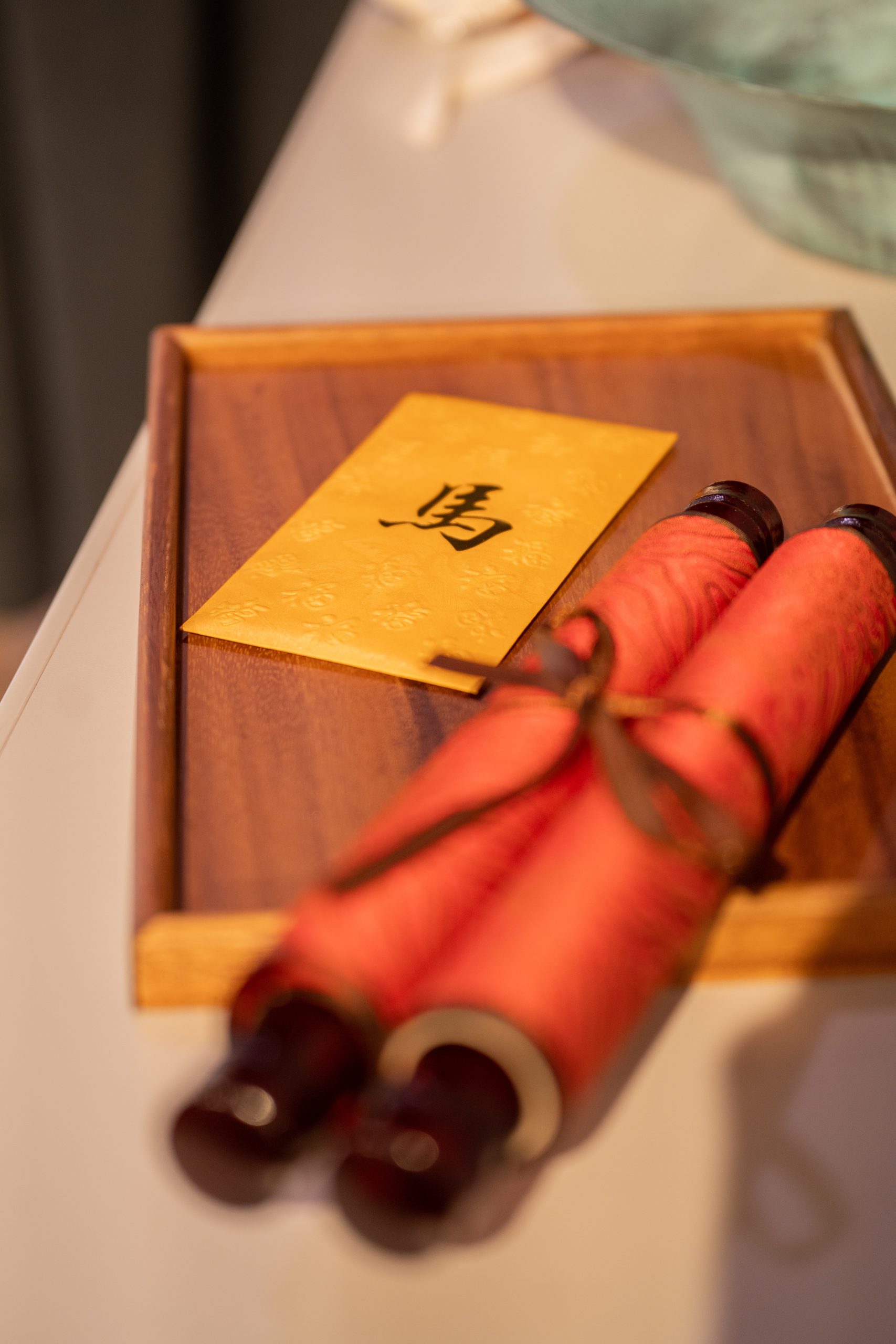 A rolled-up calligraphy scroll (red paper) on a wooden tray