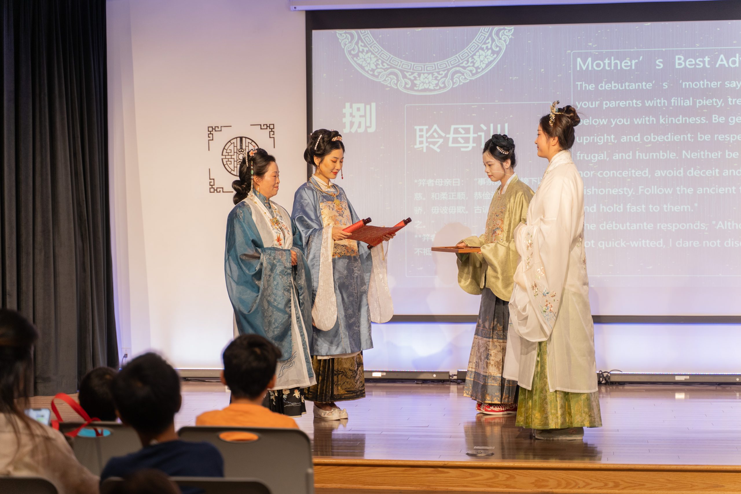 Brenda, Brenda's Mom, Audrey (the host), and a assistant all dressed in Hanfu on GCC's stage for the 'Jili' Traditional Chinese Girls' Adulthood ceremony